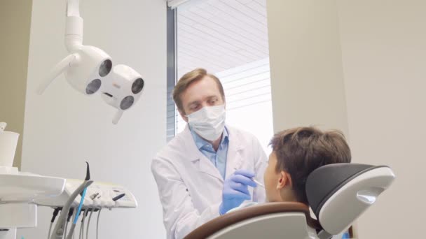 Volwassen tandarts hoge fiving zijn kleine patiënt na het controleren van zijn tanden - Video