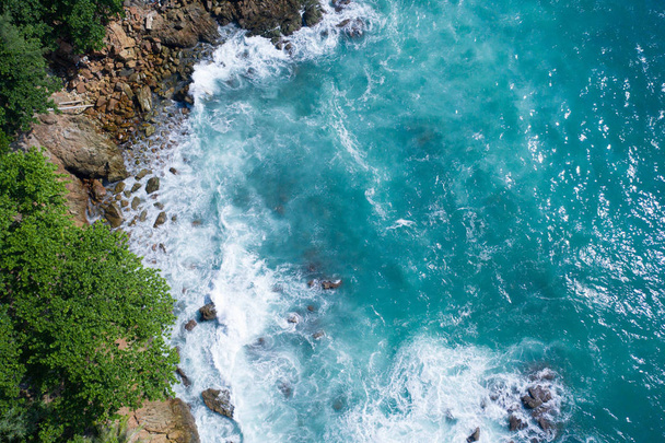 緑の木で岩の島の海岸にクラッシュする海の美しい波の空中ドローントップビュー - 写真・画像