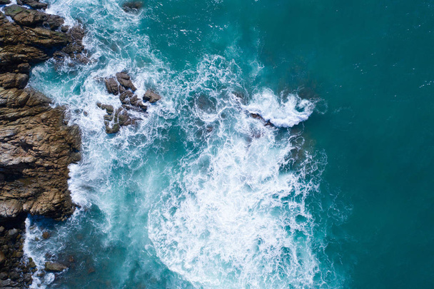 Aerial drone view of ocean's beautiful waves crashing on the rocky island coast - Foto, afbeelding