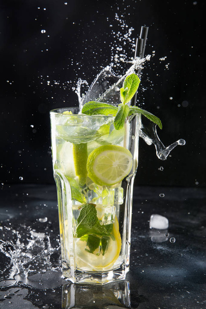 Splash of mojito cocktail or lemonade with lime and mint in glass on black. Close up. Summer drink. - Φωτογραφία, εικόνα
