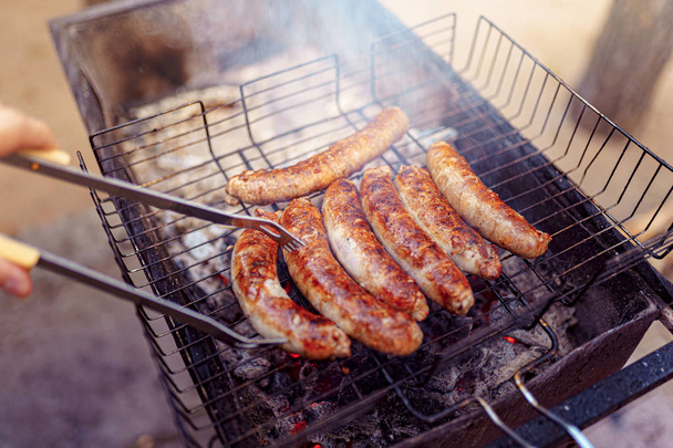 Grilled sausage on the picnic flaming grill - Foto, Imagem