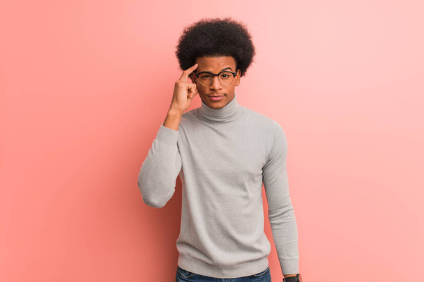 Jovem afro-americano sobre uma parede cor-de-rosa a pensar numa ideia
 - Foto, Imagem