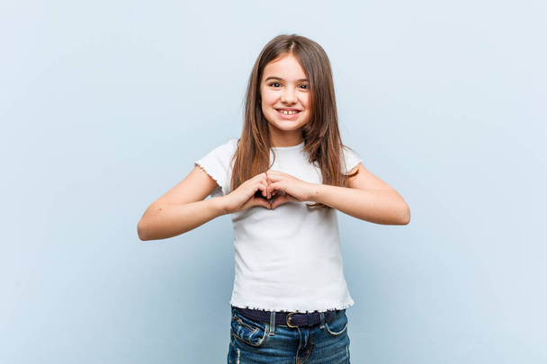 Cute girl smiling and showing a heart shape with him hands. - Foto, Imagen
