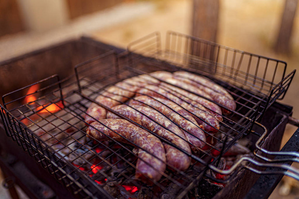 Raw sausage Grilled on the picnic flaming grill - Foto, Imagem