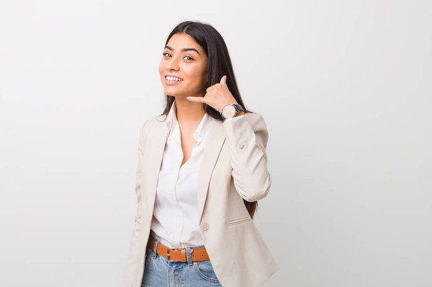 Young business arab woman isolated against a white background showing a mobile phone call gesture with fingers. - Foto, Bild