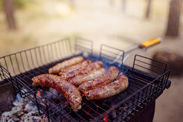 Grilled sausage on the picnic flaming grill - Foto, imagen