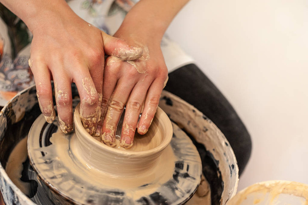 A pottery process - young girl's feminine hands making clay bowl - Foto, afbeelding