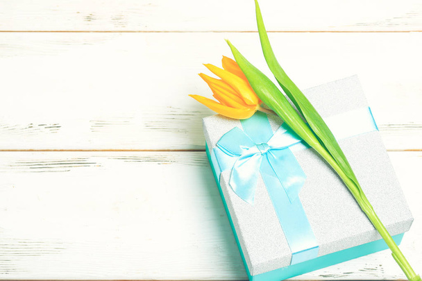greeting card yellow tulips on turquoise gift box on a white wooden background. Scandinavian style, place for text. - Zdjęcie, obraz