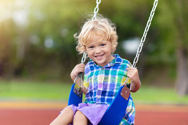 Child on playground. swing Kids play outdoor. - Фото, зображення