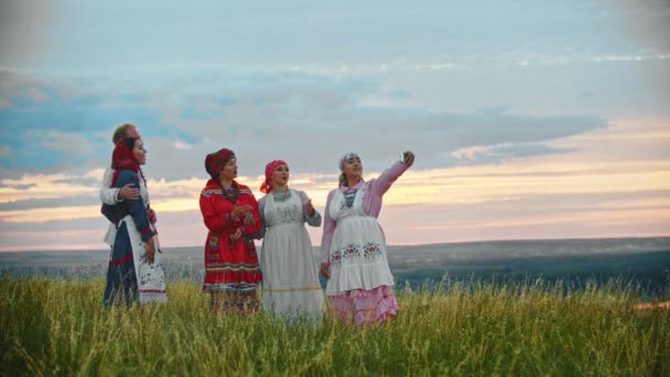 Люди в традиционной народной одежде стоят на поле и делают селфи
 - Кадры, видео