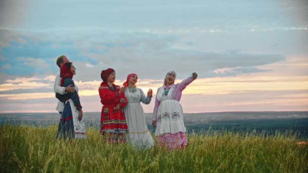 Люди в традиционной русской народной одежде стоят на поле и делают селфи
 - Кадры, видео