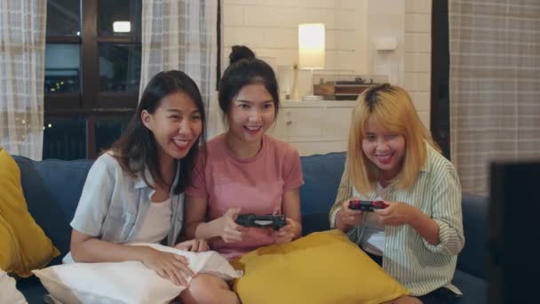 Asyalı kadın çift grubu evde oyun oynamak, kadın joystick kullanarak gece oturma odasında kanepede birlikte komik an sahip. Genç arkadaş futbol fan, tatil konsepti kutlamak. - Video, Çekim