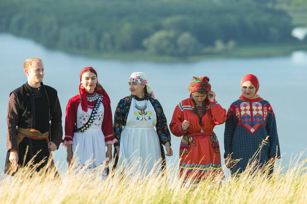 Menschen in traditioneller russischer Kleidung stehen auf dem Feld - ein Mann mit einer Balalaika - Foto, Bild