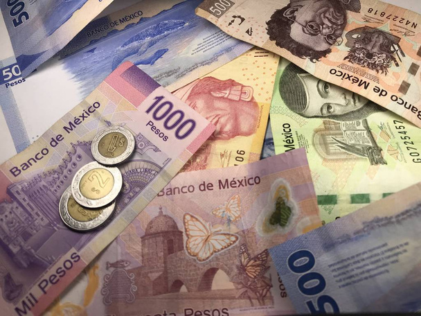 Muchos billetes mixtos de peso mexicano repartidos sobre un escritorio de madera
 - Foto, Imagen
