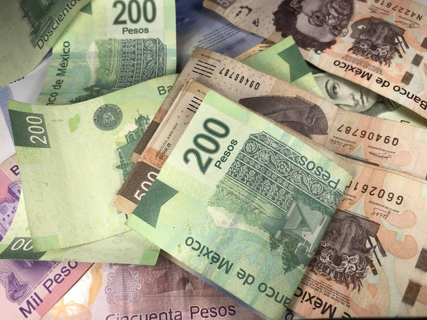 Veel gemengde Mexicaanse peso-biljetten verspreid over een houten bureau - Foto, afbeelding