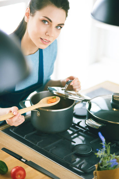 Cooking woman in kitchen with wooden spoon - Фото, изображение