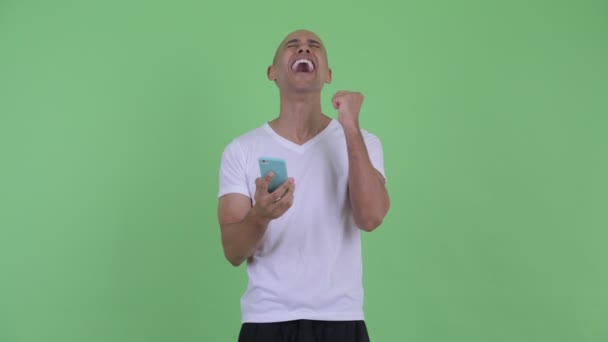 Happy handsome bald man using phone and getting good news - Metraje, vídeo
