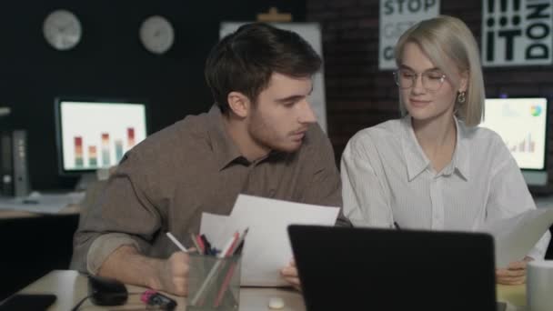 Partenaire d'affaires discutant de rapports financiers devant un ordinateur portable dans un bureau de nuit - Séquence, vidéo