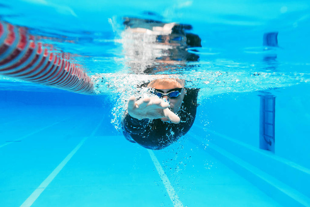underwater view of professional male swimmer training in swimming pool - Zdjęcie, obraz