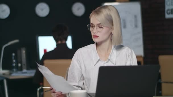 Serious business woman working with financial document in late office - Séquence, vidéo