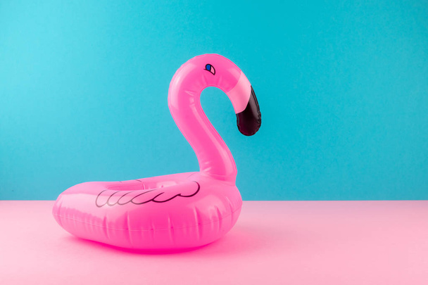 aufblasbarer rosa Flamingo auf pastellblauem und rosa Hintergrund. Pool-Float-Party, trendiges Sommerkonzept. flache Lage, Kopierraum. - Foto, Bild