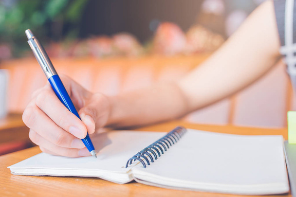 Mulher mão escrevendo em um bloco de notas com uma caneta no escritório
. - Foto, Imagem
