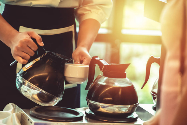 Hand waitress pour coffee in cup at the hotel in the morning. - 写真・画像