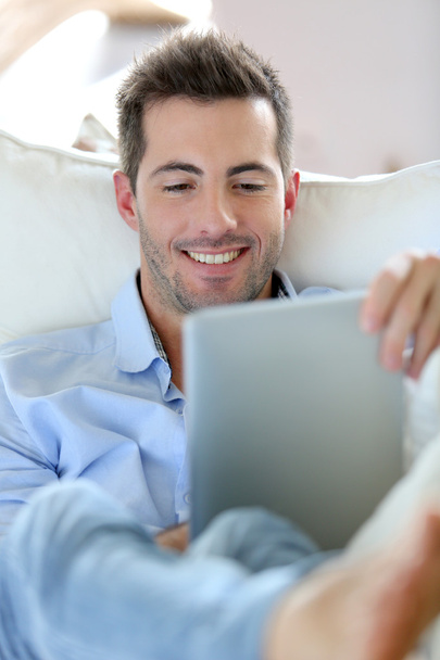 Joven alegre acostado en un sofá con una tableta digital
 - Foto, Imagen