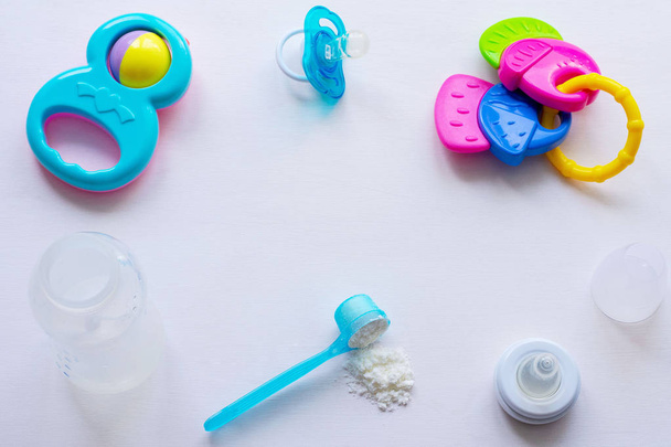 Leche en polvo para bebés, biberón y juguetes para niños sobre un fondo claro
 - Foto, Imagen