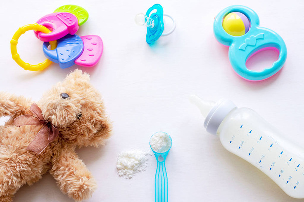Sušené mléko, dětská láhev a dětské hračky na světlém pozadí položte - Fotografie, Obrázek