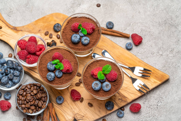 Classic tiramisu dessert with blueberries and raspberries in a glass on concrete background - Photo, Image