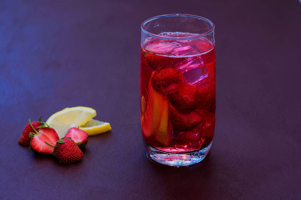 Drink with ice from strawberries on a dark background. Fresh strawberry cocktail. Fresh summer cocktail with strawberry and ice cubes. Glass of strawberry soda drink on dark background. - Photo, Image