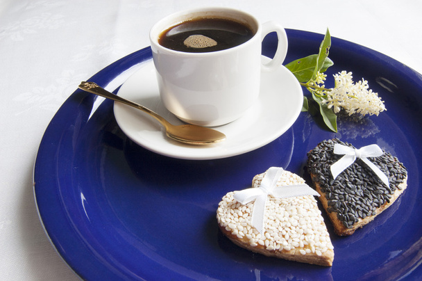 Два свадебных печенья с чашкой кофе на голубой тарелке
 - Фото, изображение