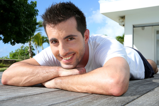 Man relaxing on pool deck after exercising - Foto, Bild