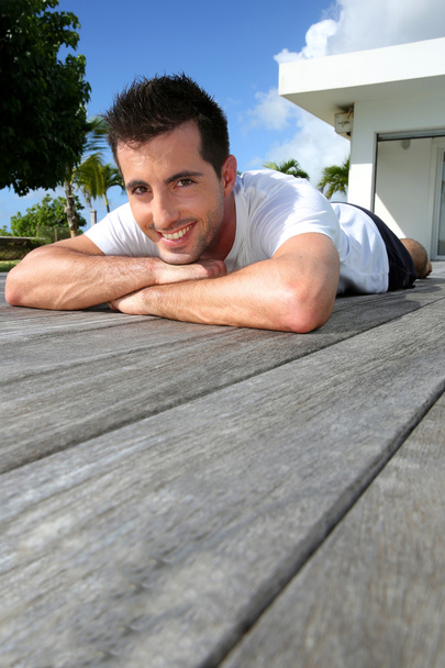 Man relaxing on pool deck after exercising - Foto, Bild