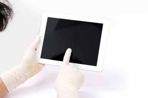 Imagen de un hombre usando guantes de laboratorio y sosteniendo una tableta en la mano. Aislado sobre fondo blanco
. - Foto, imagen