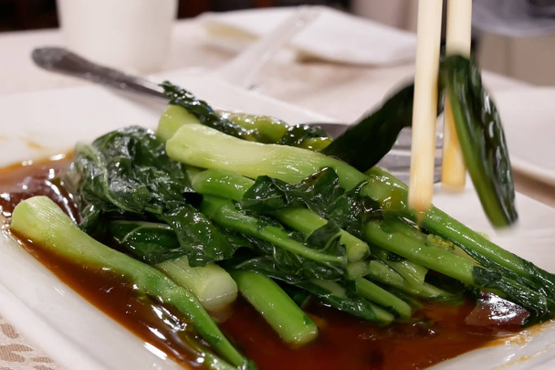 Movimiento de personas comiendo verduras en la mesa dentro del restaurante chino
 - Foto, imagen