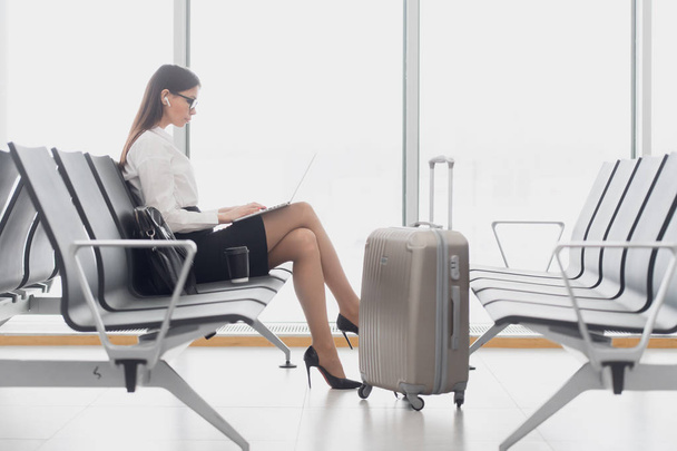 Üzleti nő használ laptopot a repülőtéren ül az ablakon - Fotó, kép