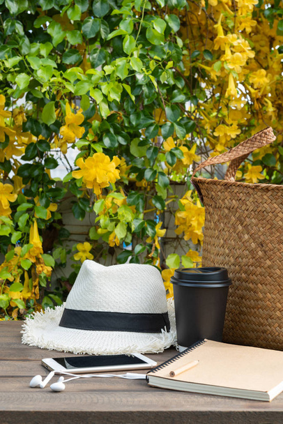 Kahvikuppi, muistikirja, puhelin, Panama hattu ja rottinki laukku puinen ta
 - Valokuva, kuva