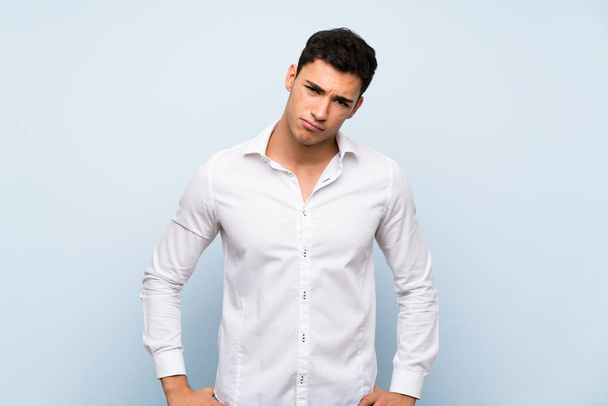 Handsome man over blue wall with sad and depressed expression - Photo, image