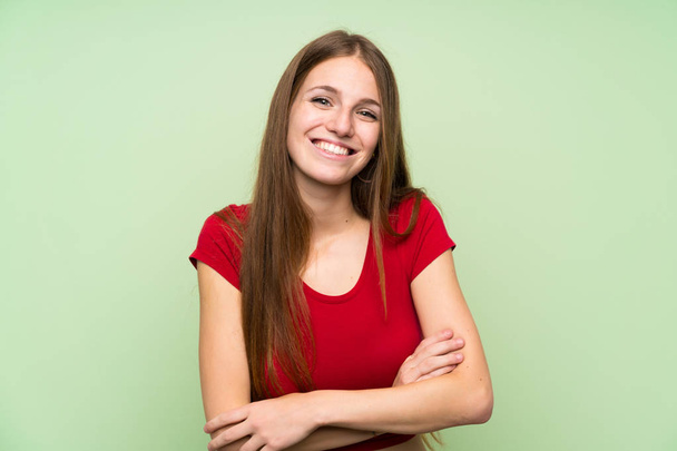 Fiatal nő, hosszú hajú, elszigetelt zöld fal nevetve - Fotó, kép
