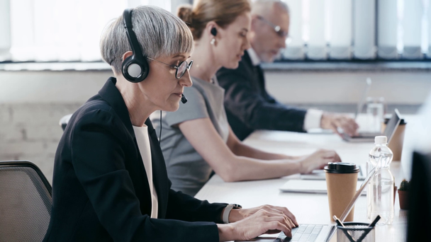 selectieve focus van telewerker praten tijdens het raadplegen en het gebruik van laptop in de buurt van collega's in Office  - Video