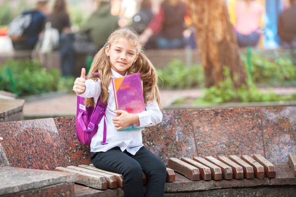 Schoolmeisje met een rugzak en boek buiten. Onderwijs-en Leerconcept. - Foto, afbeelding