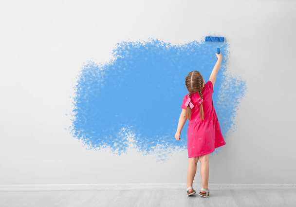 Little girl painting wall in room - Фото, изображение