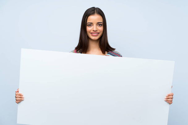 Молода жінка над ізольованою синьою стіною тримає порожній білий плакат для вставки концепції
 - Фото, зображення