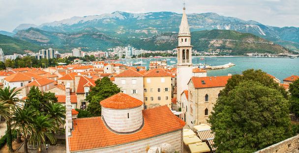 Πανόραμα του δημοφιλούς θέρετρου Μπούντβα, Μαυροβουνίου, τα αρχαία τείχη και οροφή με κόκκινα κεραμίδια, ο κόλπος της Αδριατικής θάλασσας και τα Βαλκάνια Όρη. - Φωτογραφία, εικόνα