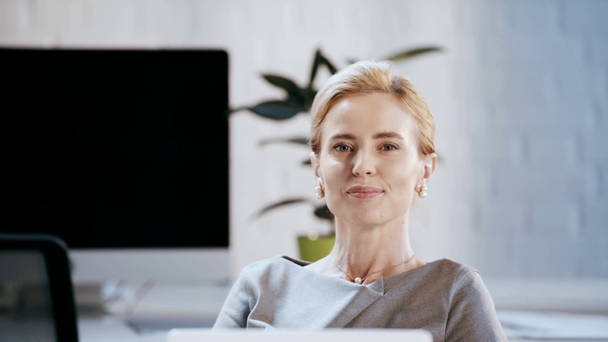 счастливая деловая женщина в формальной одежде улыбается и смотрит в камеру в офисе
  - Кадры, видео