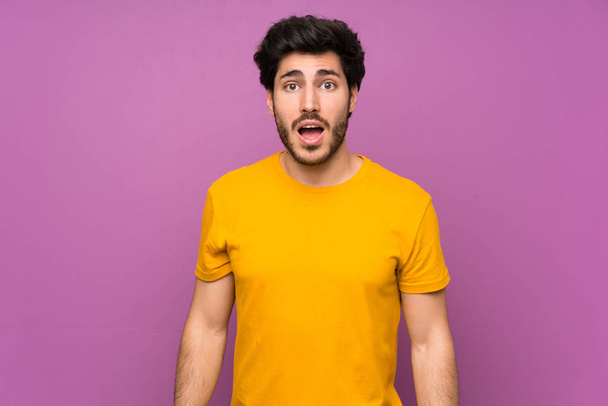 Handsome over isolated purple wall with surprise facial expression - Photo, Image