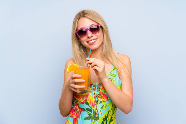 Young woman in swimsuit over blue background with a cocktail - Foto, immagini