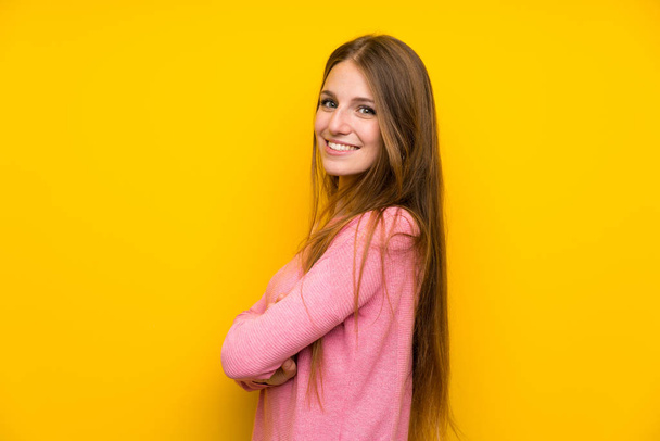 Молода жінка з довгим волоссям над ізольованою жовтою стіною з схрещеними руками і з нетерпінням чекає
 - Фото, зображення